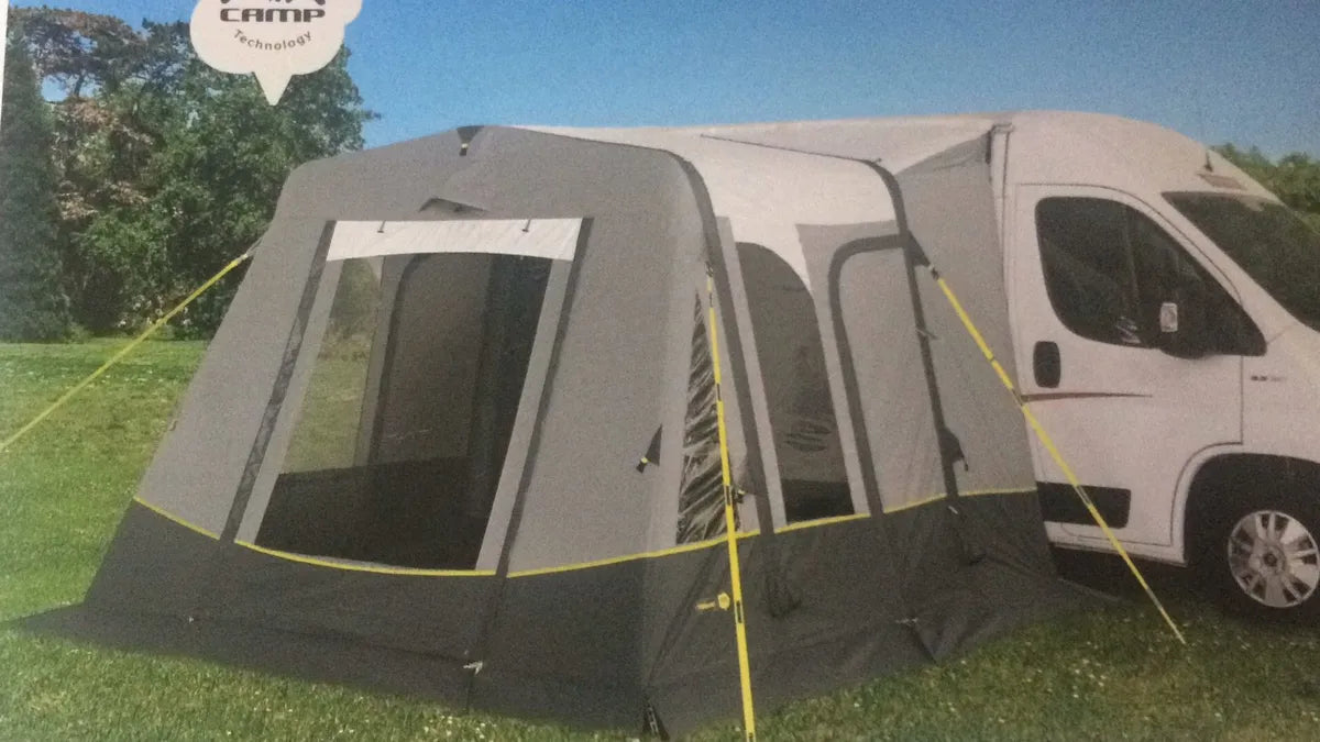 The Trigano Bali inflatable awning is connected to a van outdoors. pegged and setup.