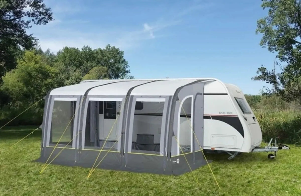 A render of the Trigano Aruba Air Awning connected to a caravan in the outdoors.