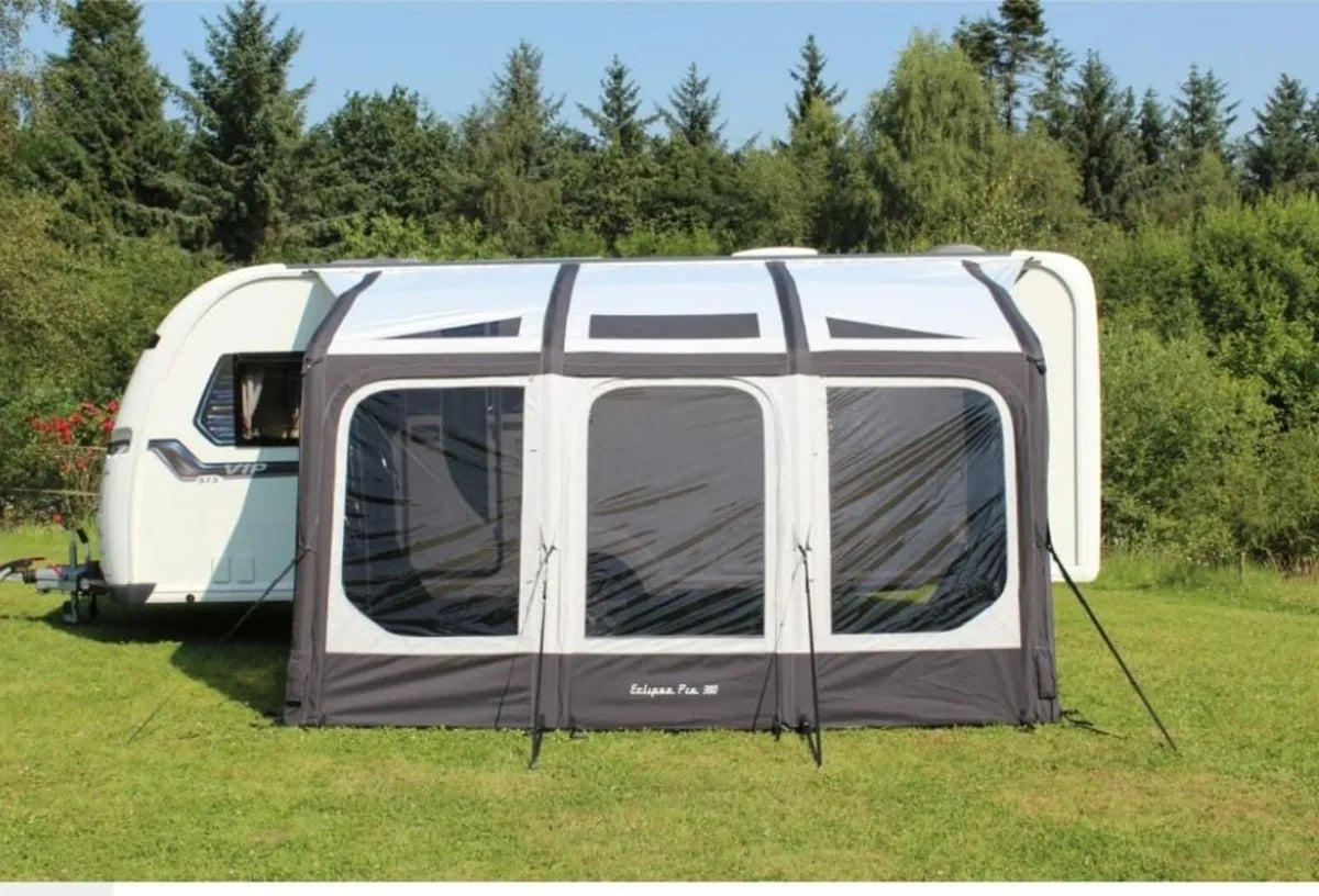 The Eclipse pro 380L Air Awning is pitched up beside a caravan with three panels, front view